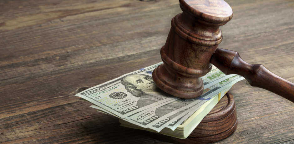 judge's gavel leaning on pile of American dollars