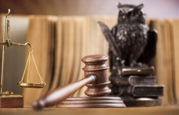 judge's gavel, justice scales and a figure of an owl